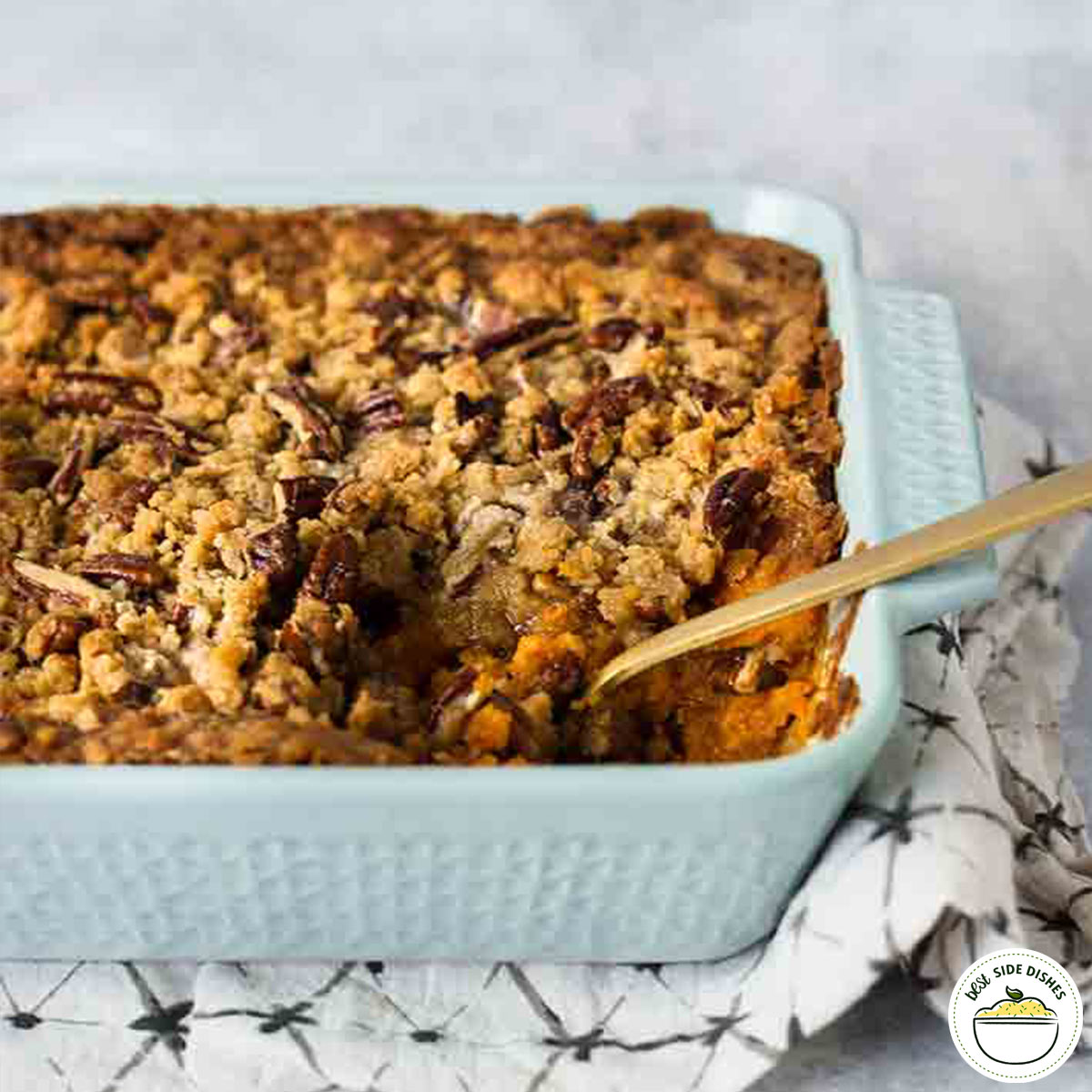 Sweet potato casserole in a light blue dish with a wooden spoon
