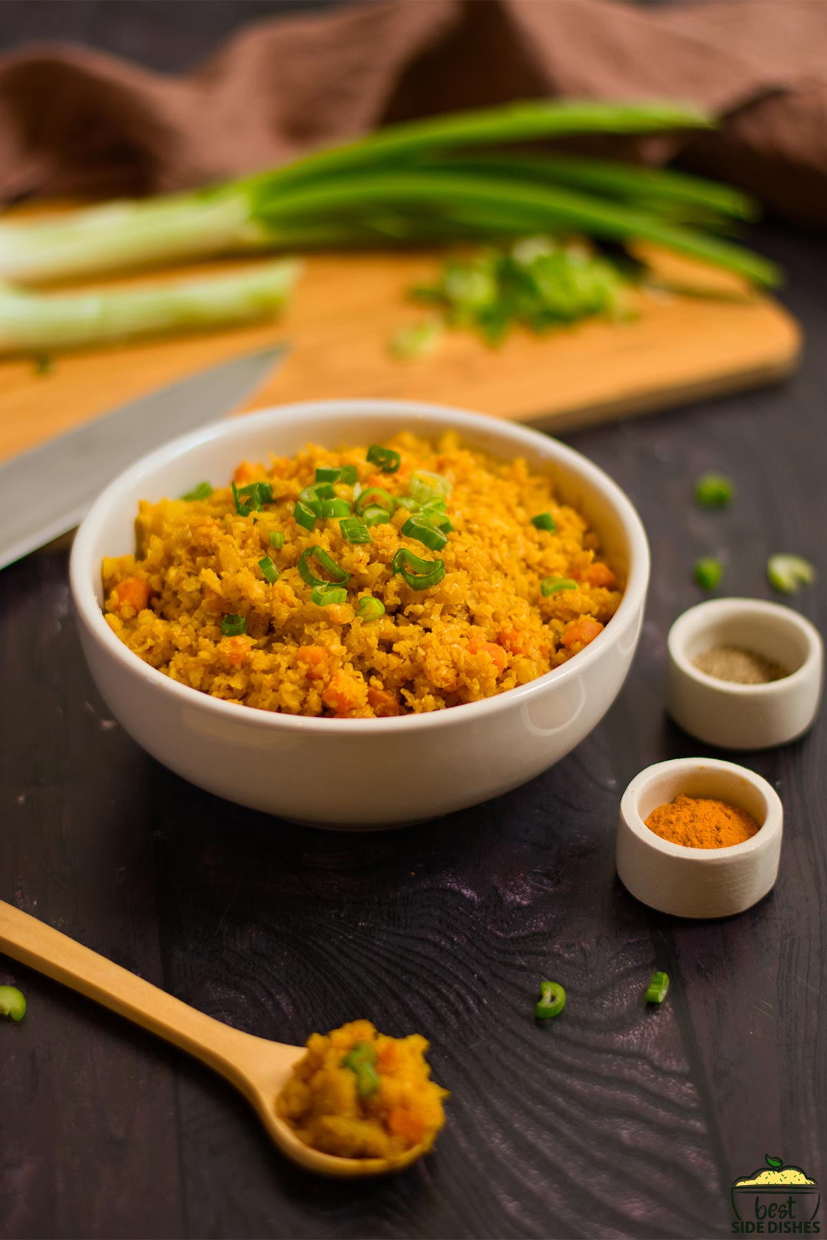 Turmeric cauliflower rice in a bowl with spring onions at the back