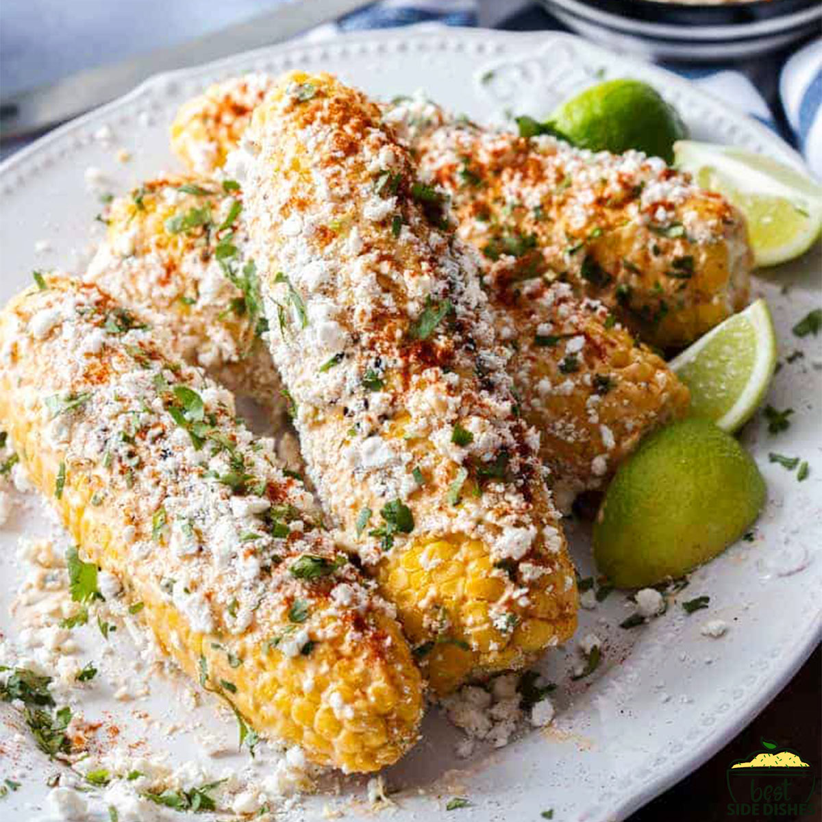 Mexican street corn on a white plate with limes