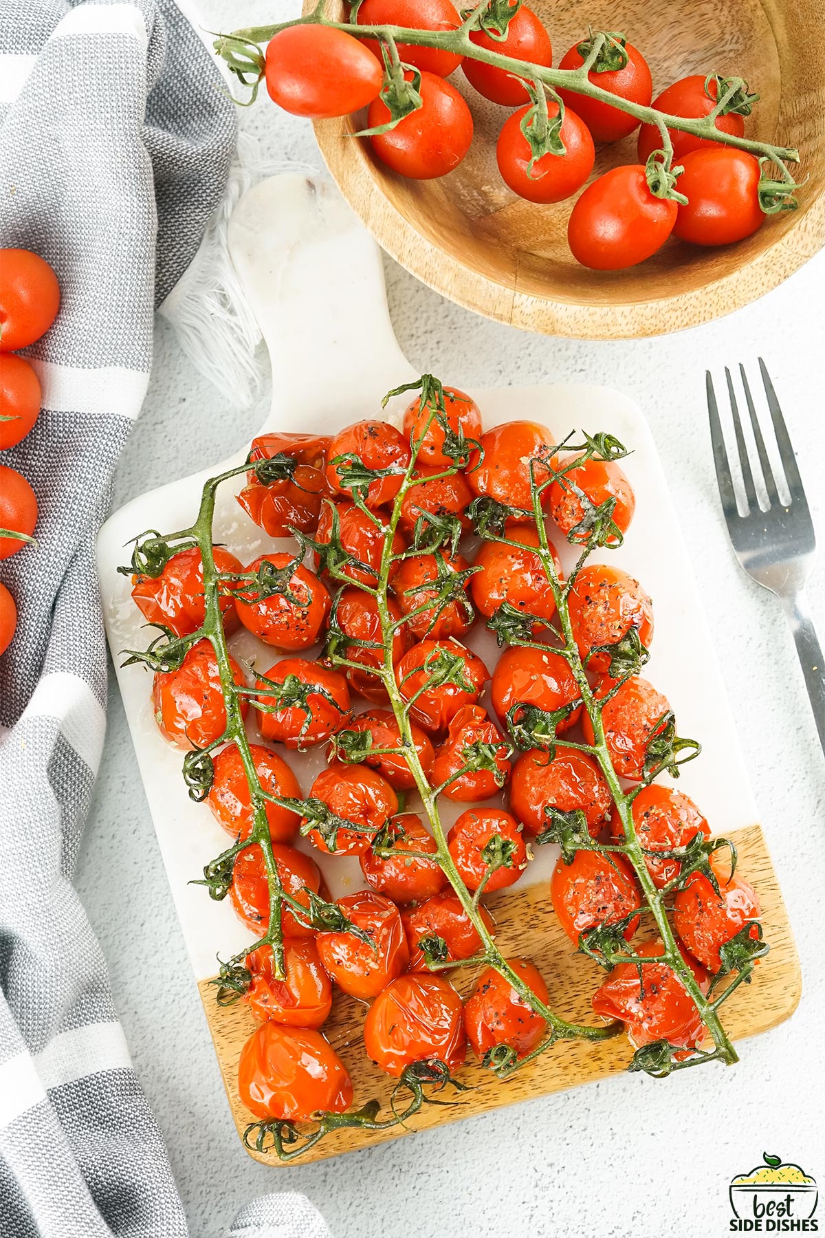 Roasted tomatoes on a white surface with a fork