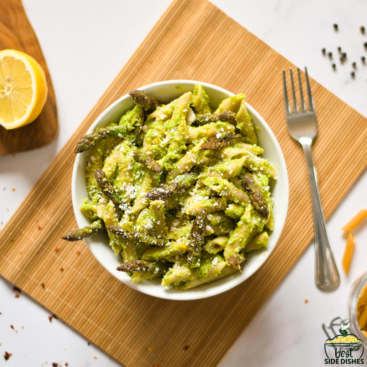 asparagus pasta in a bowl with a lemon and a fork