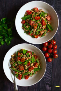 Two white bowls of mediterranean bean salad