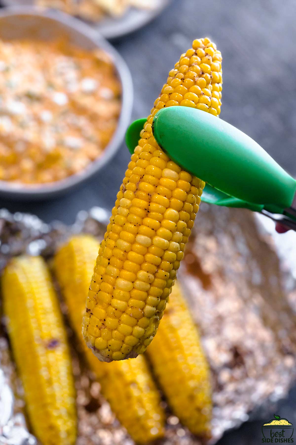 lifting a grilled corn cob with tongs