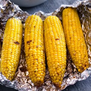 four corn on the cob in foil ready to eat