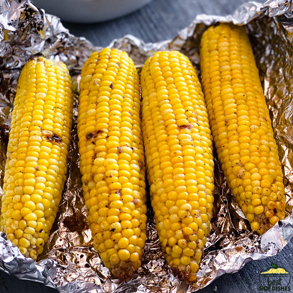 four corn on the cob in foil ready to eat