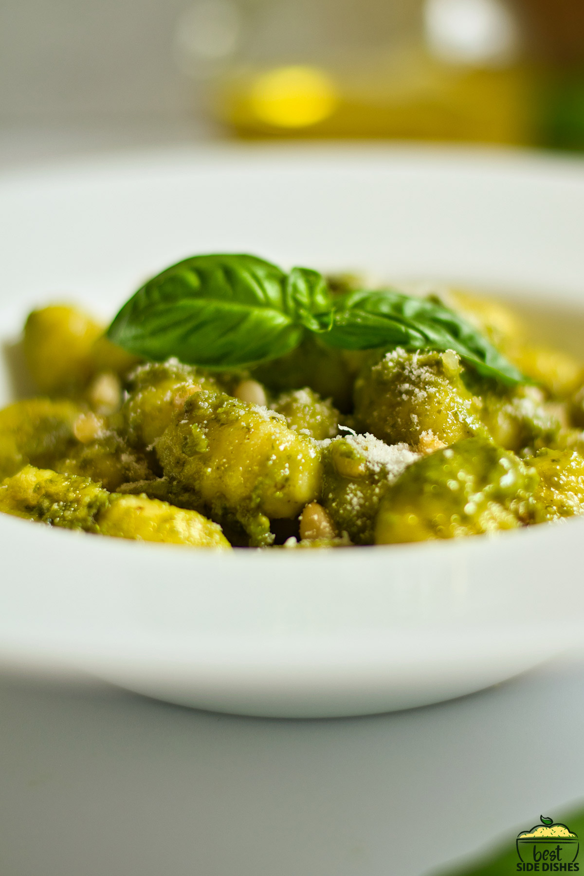 pesto gnocchi in a white bowl with a piece of basil on top