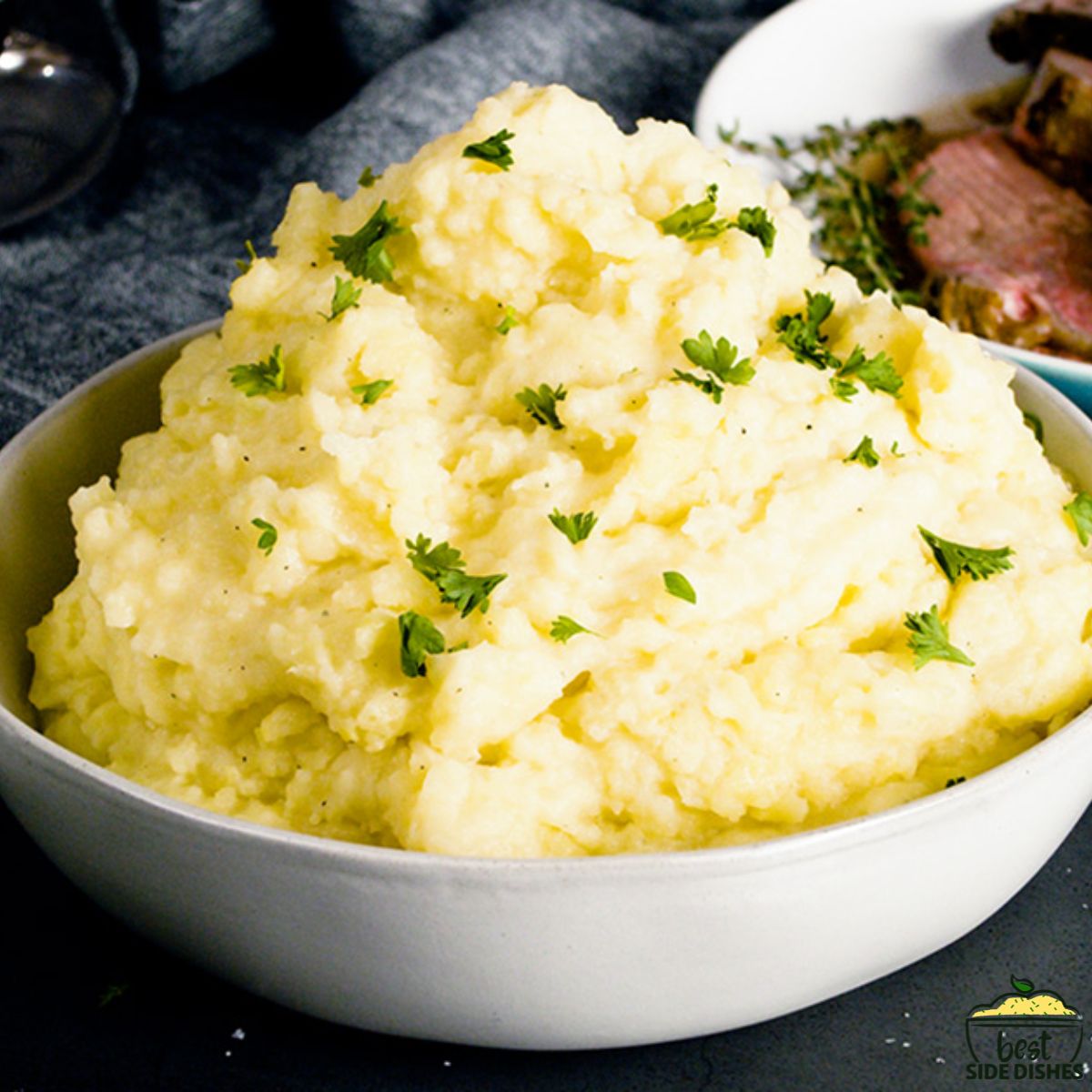 Creamiest mashed potatoes in a white bowl topped with chives