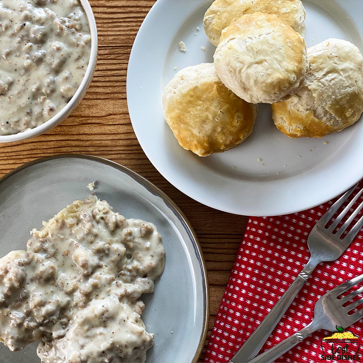 4 biscuits on a white plate with sausage gravy and a red napkin