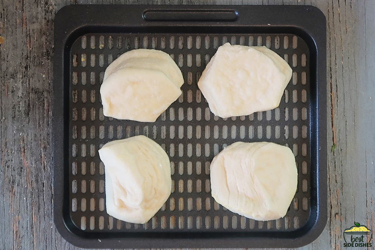 4 uncooked biscuits on an air fryer baking tray