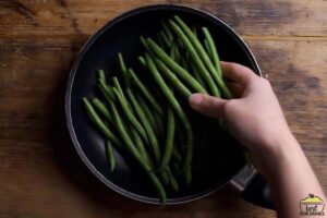 adding green beans to skillet