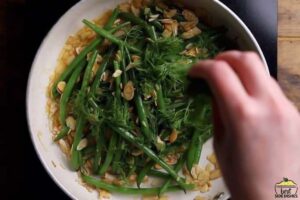 adding dill to green bean amandine in a skillet