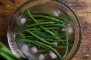 adding green beans to ice water to blanch them