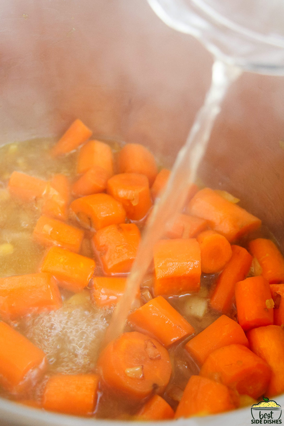 broth being poured into an instant pot full of carrots and onions