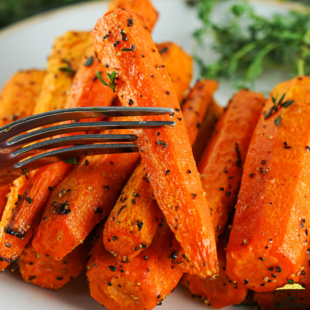 a fork holding up an air fryer carrot over a plate of carrots