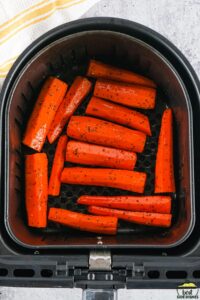 seasoned raw carrots in an air fryer basket