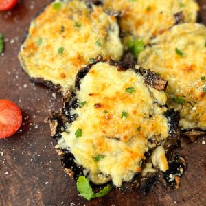 a closeup of stuffed mushrooms and tomatoes on a cutting board