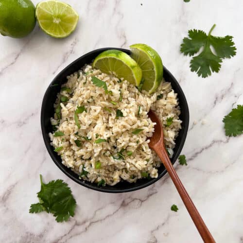 cilantro lime rice in a black bowl with lime wedges on top