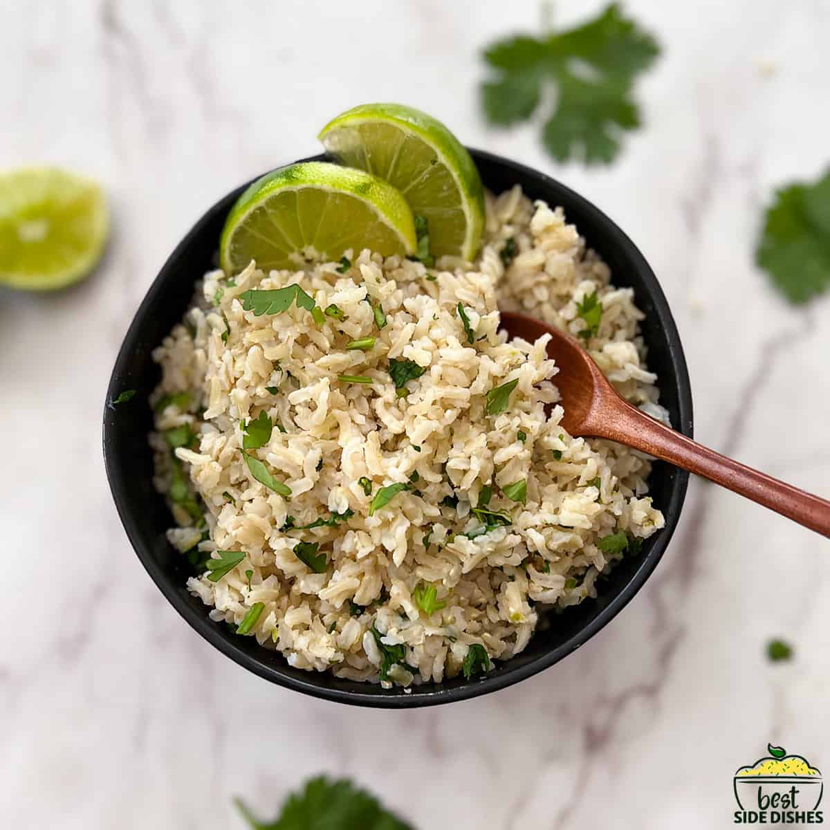 cilantro lime rice in a black bowl with a wooden spoon
