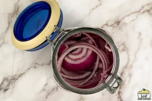 sliced red onions in a glass jar
