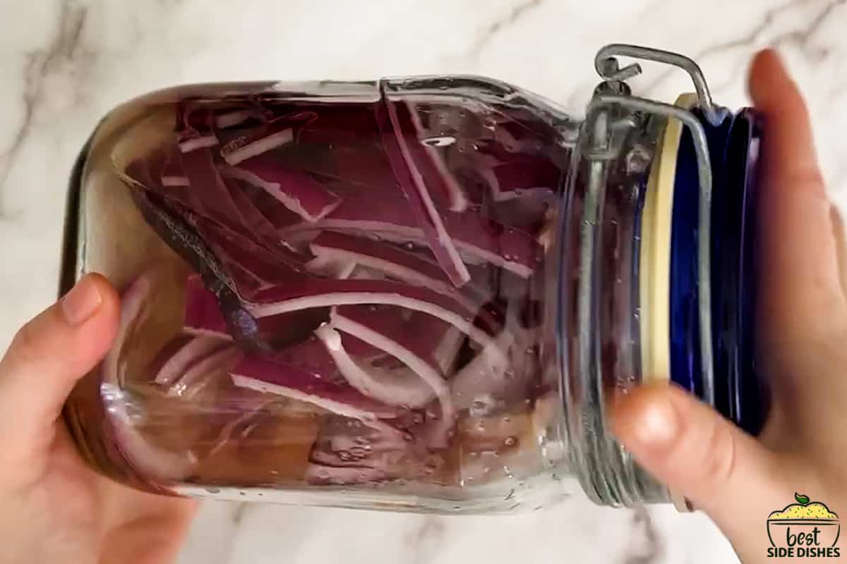 shaking a clear jar with pickled red onions