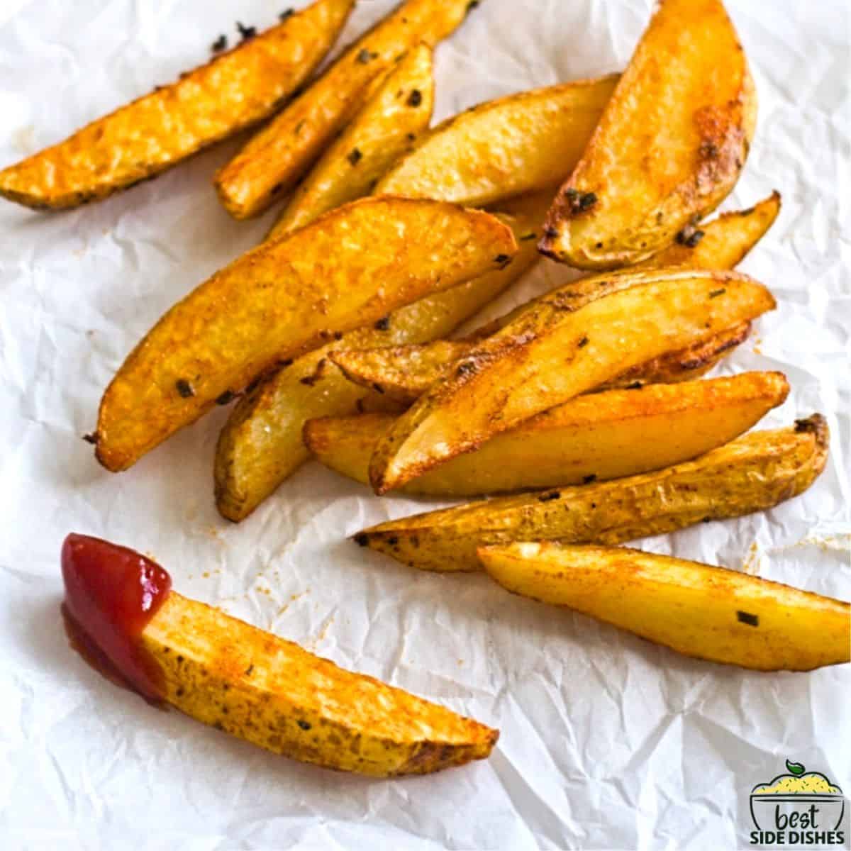 Crispy potato wedges in a pile, one dipped in ketchup