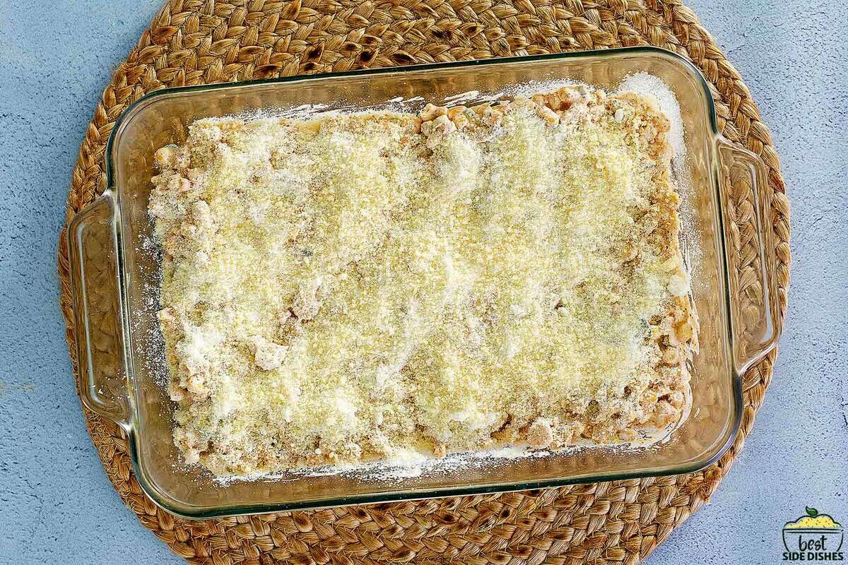 unbaked corn casserole in a glass dish covered with parmesan