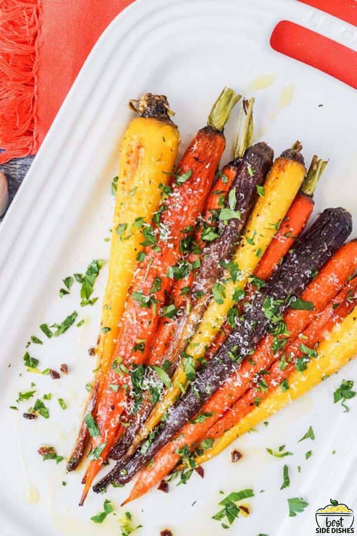 rainbow carrots on a white plate with herbs and parmesan cheese
