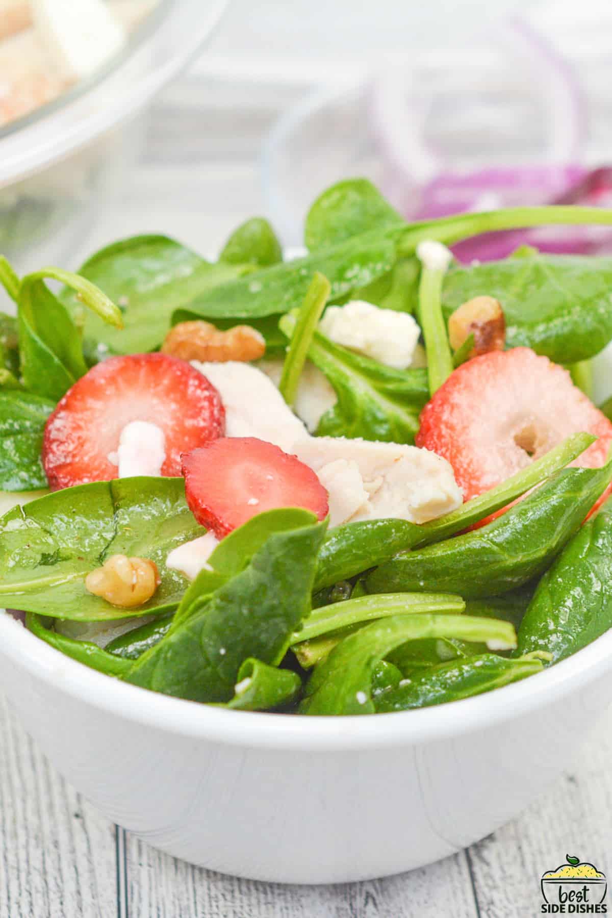 close up of spinach salad in a white dish