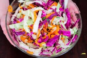 the ingredients for chinese slaw in a mixing bowl after being mixed