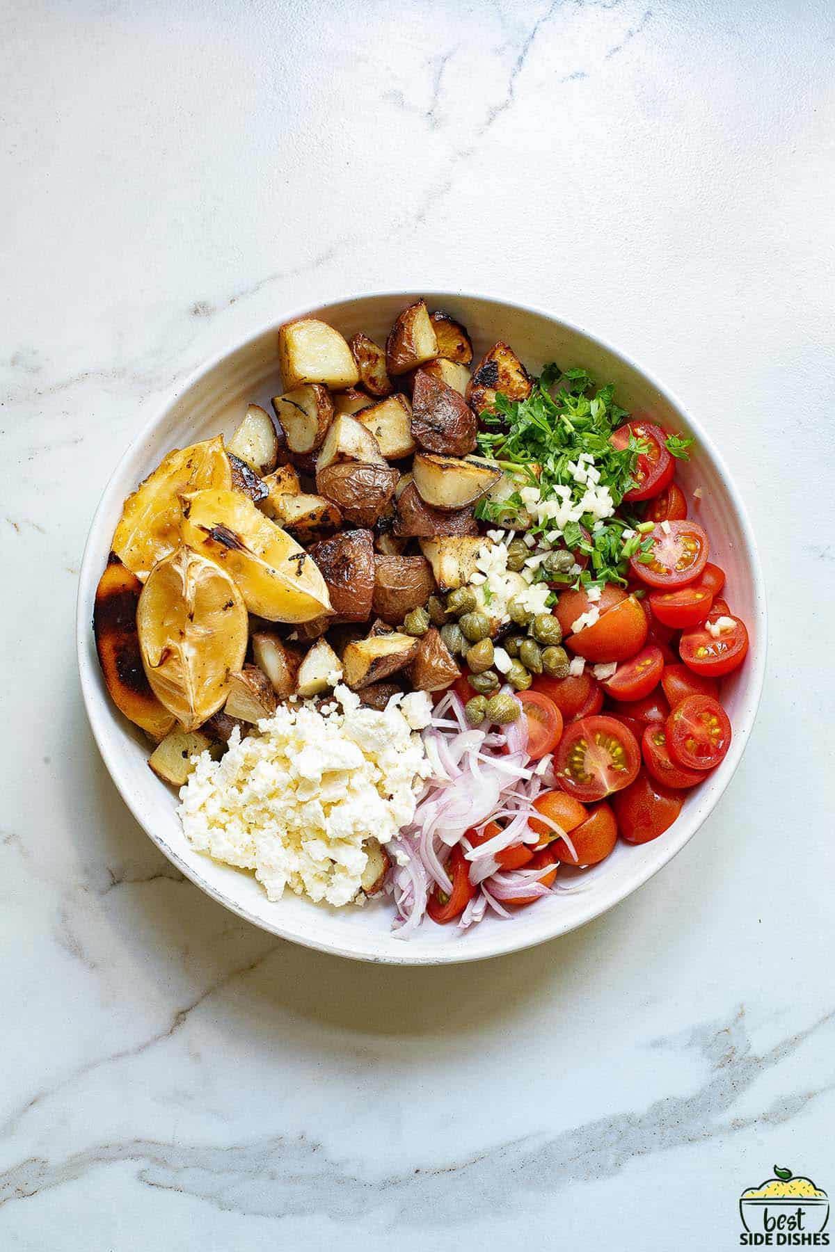 greek potato salad unmixed in a bowl