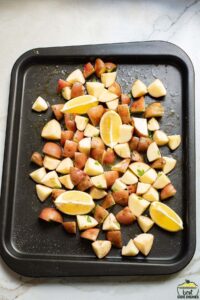 potatoes and lemon wedges on a baking sheet ready to roast