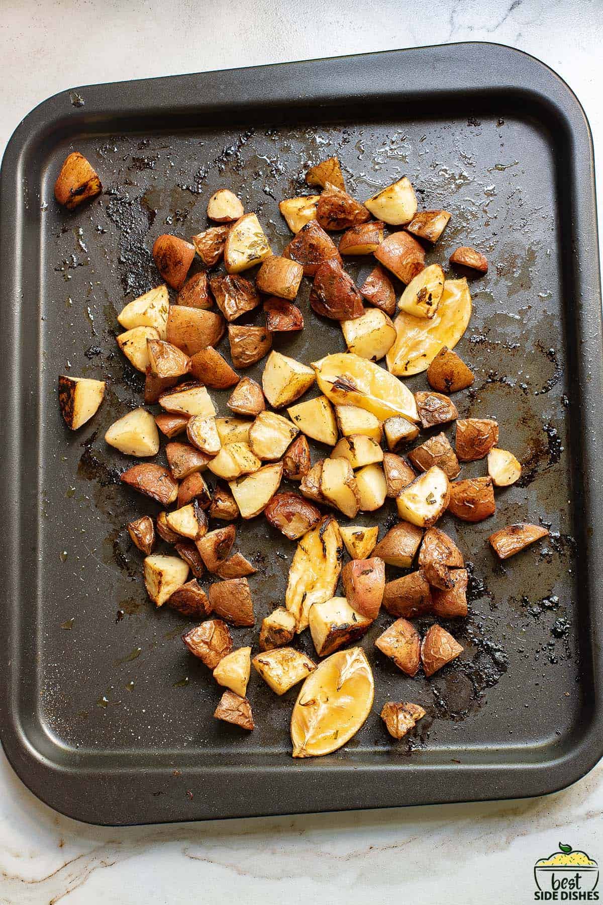 roasted potatoes and lemon wedges on a baking sheet