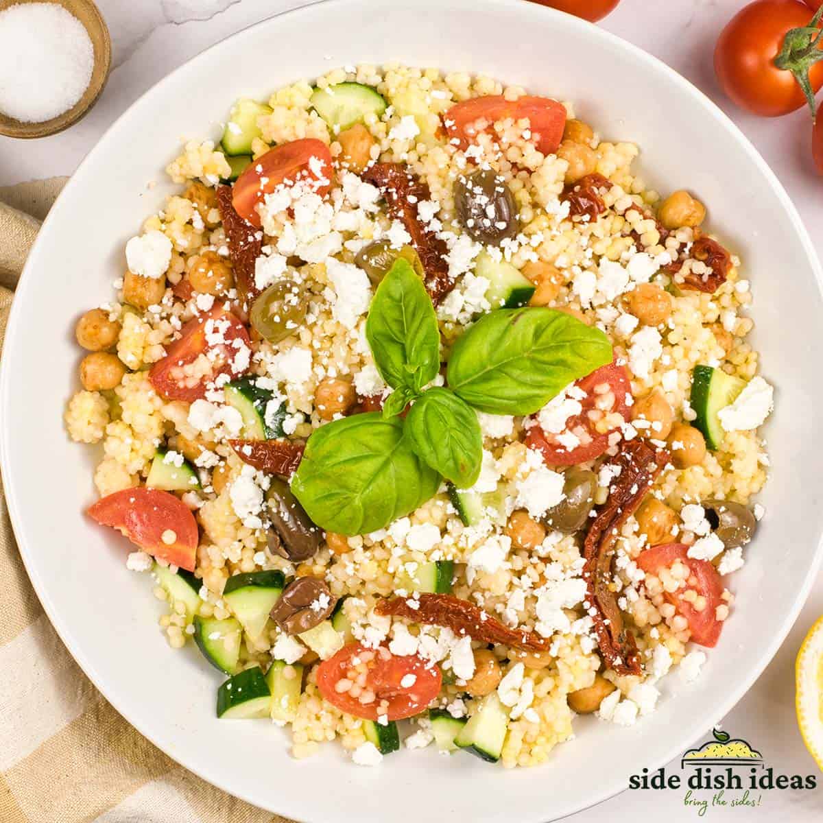 a bowl of mediterranean couscous salad with basil on top