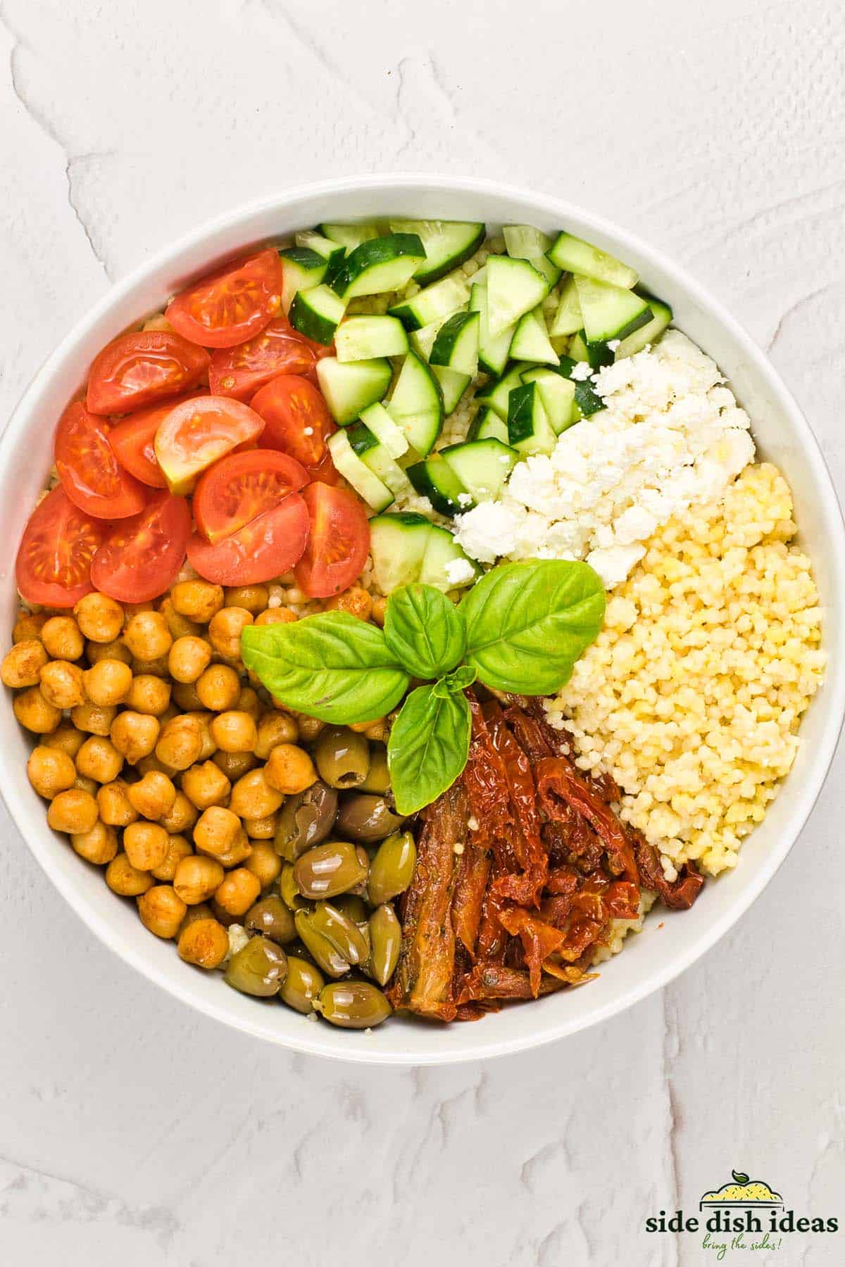 mediterranean couscous salad ingredients in a bowl before mixing