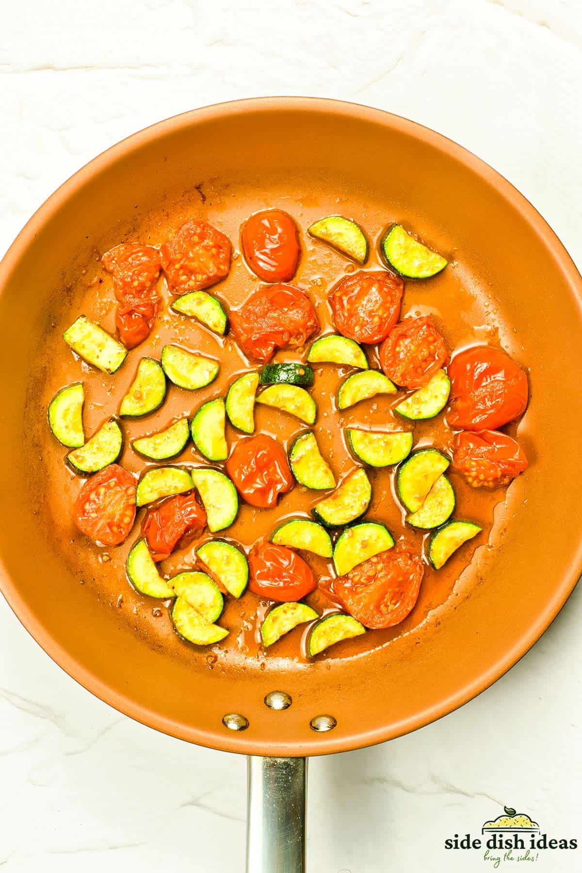 zucchini and tomatoes sauteed in a pan