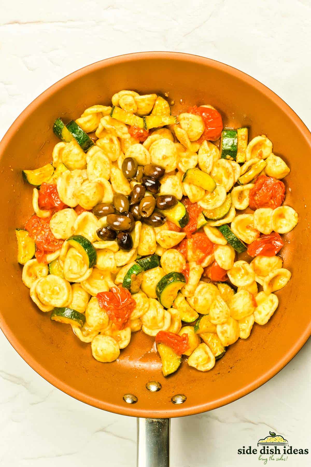 olives added to the pan of pasta and vegetables