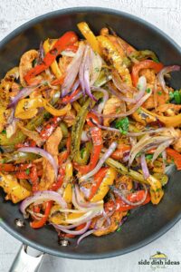 fajita vegetables in a pan with chicken and cilantro