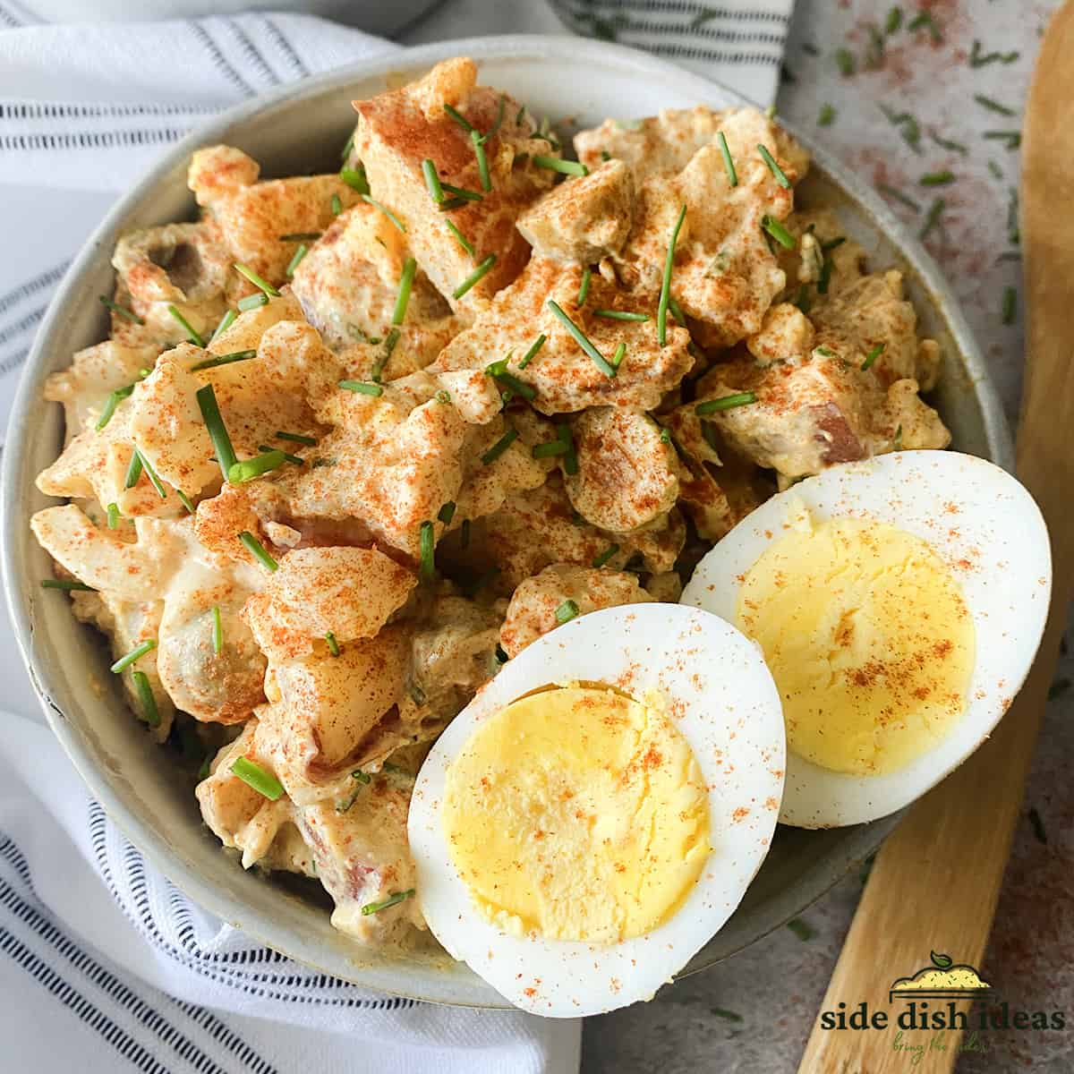 potato salad with mustard, paprika and chives in a bowl with hard boiled egg slices
