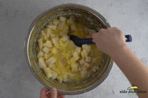 folding cubed bread into pineapple casserole mixture