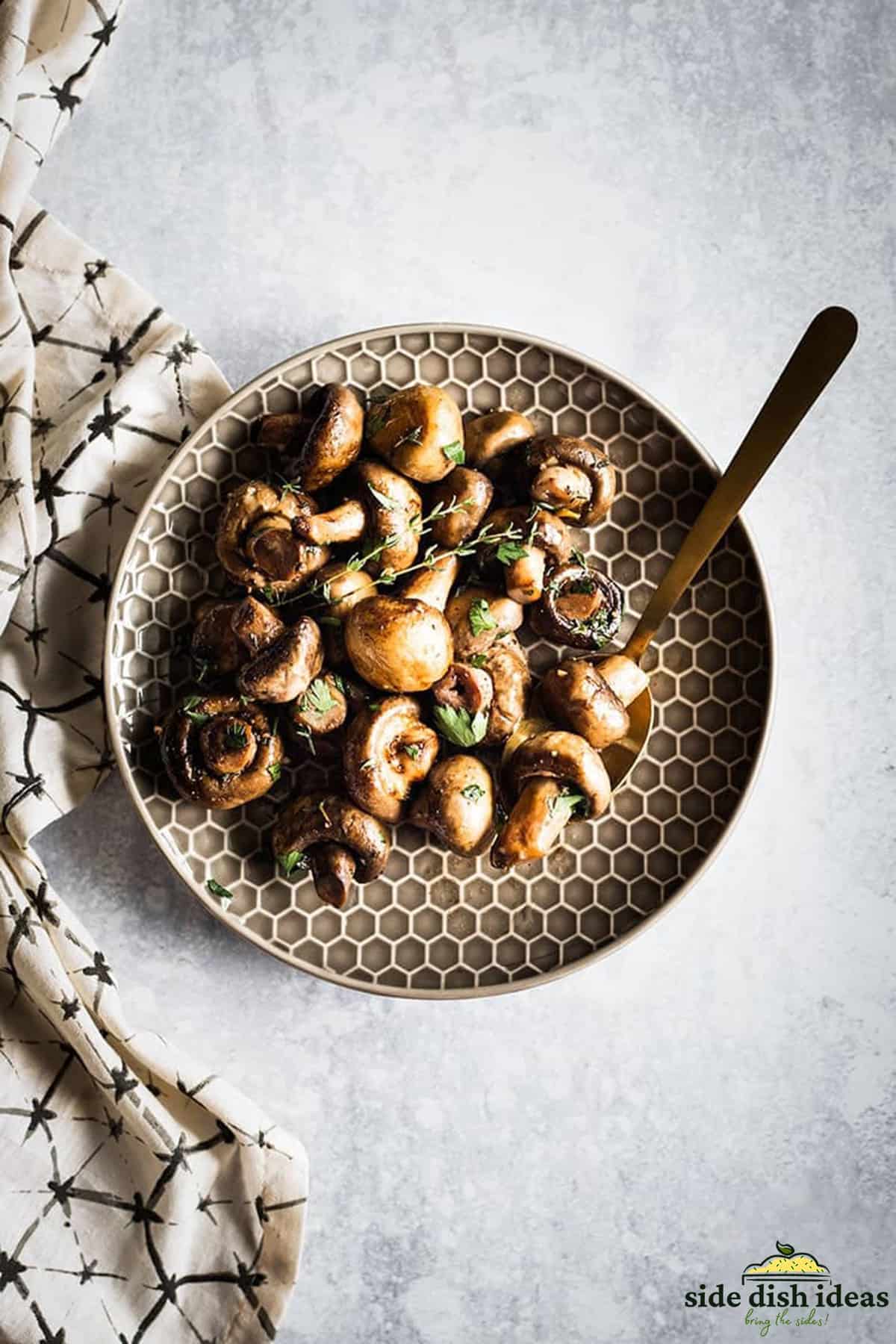 white button mushrooms on a plate with fresh herbs