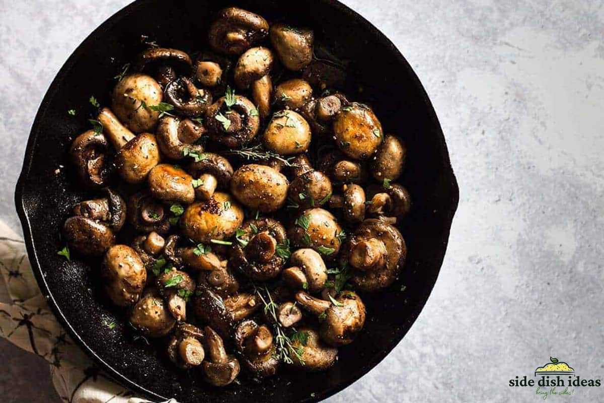 whole button mushrooms cooked in a skillet with herbs