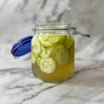 pickled cucumbers inside of a glass jar with the lid open