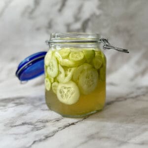 pickled cucumbers inside of a glass jar with the lid open