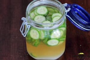 adding ingredients into glass jar for pickled cucumbers