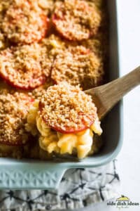 baked mac and cheese in a dish with a wooden spoon