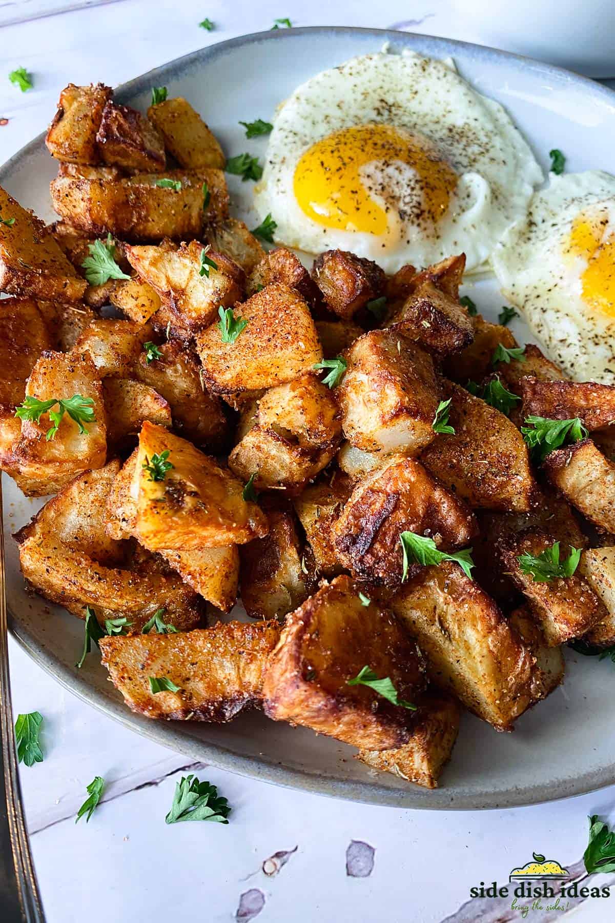 seasoned potatoes on a white plate with sunny side up eggs