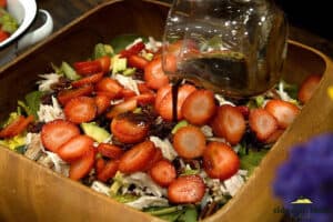 pouring dressing over strawberry salad