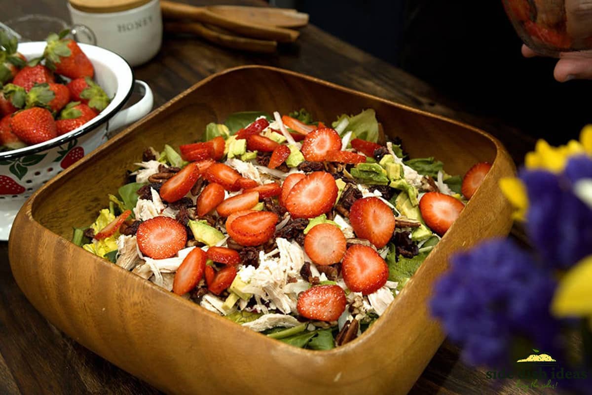 strawberry salad in a wooden square bowl with nuts and chicken