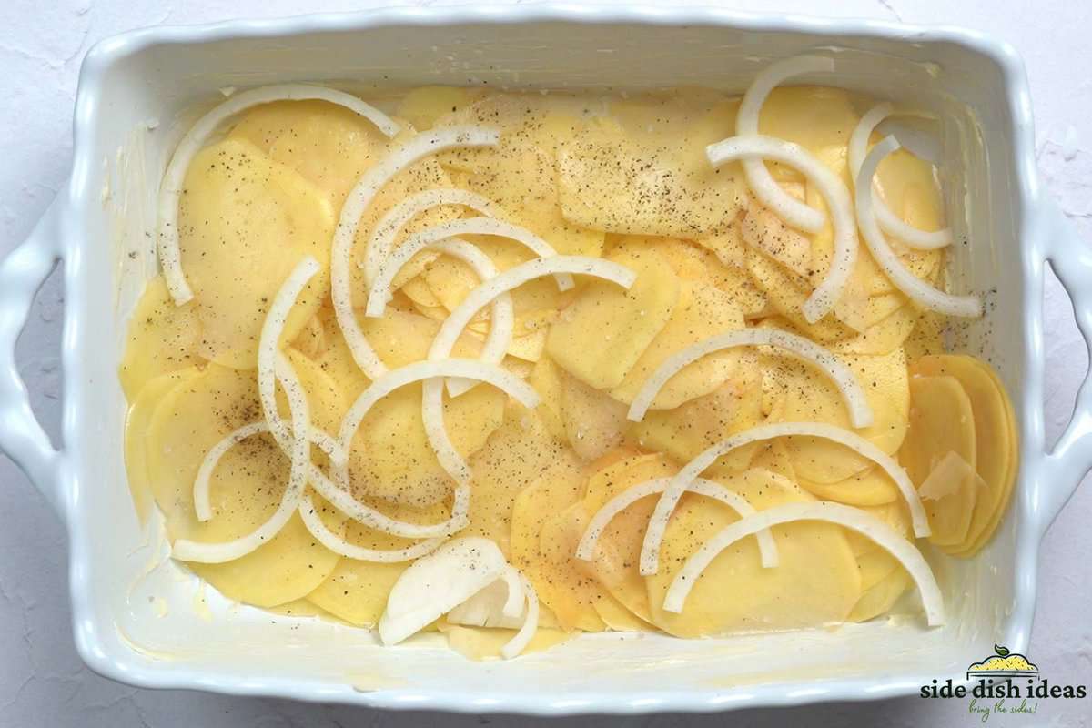 adding sliced potatoes and onions inside of baking dish
